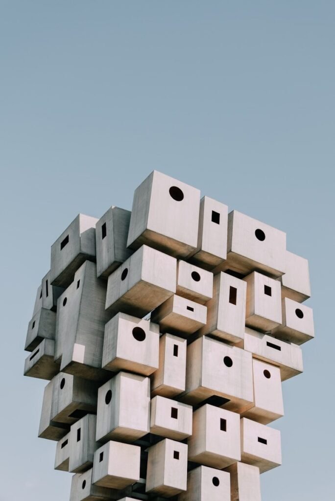 Abstract sculpture of stacked concrete blocks against a clear sky.